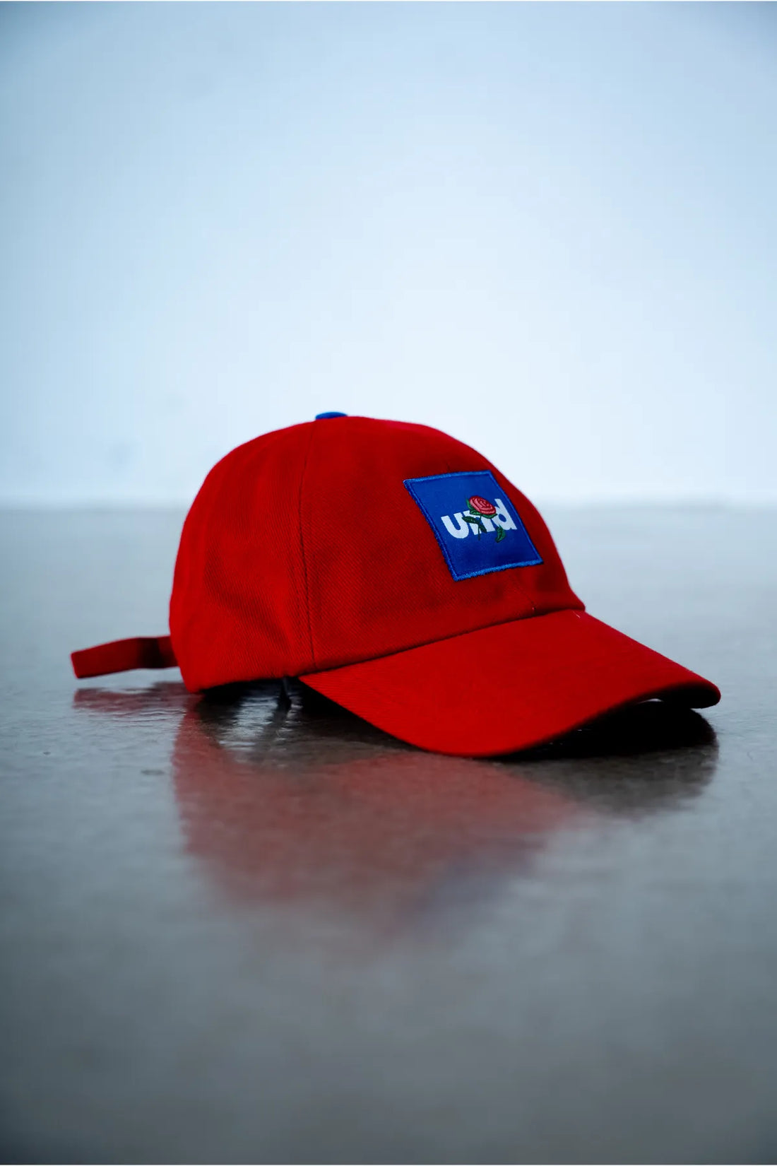 Und red cap with "und rose embroidery" in blue badge.